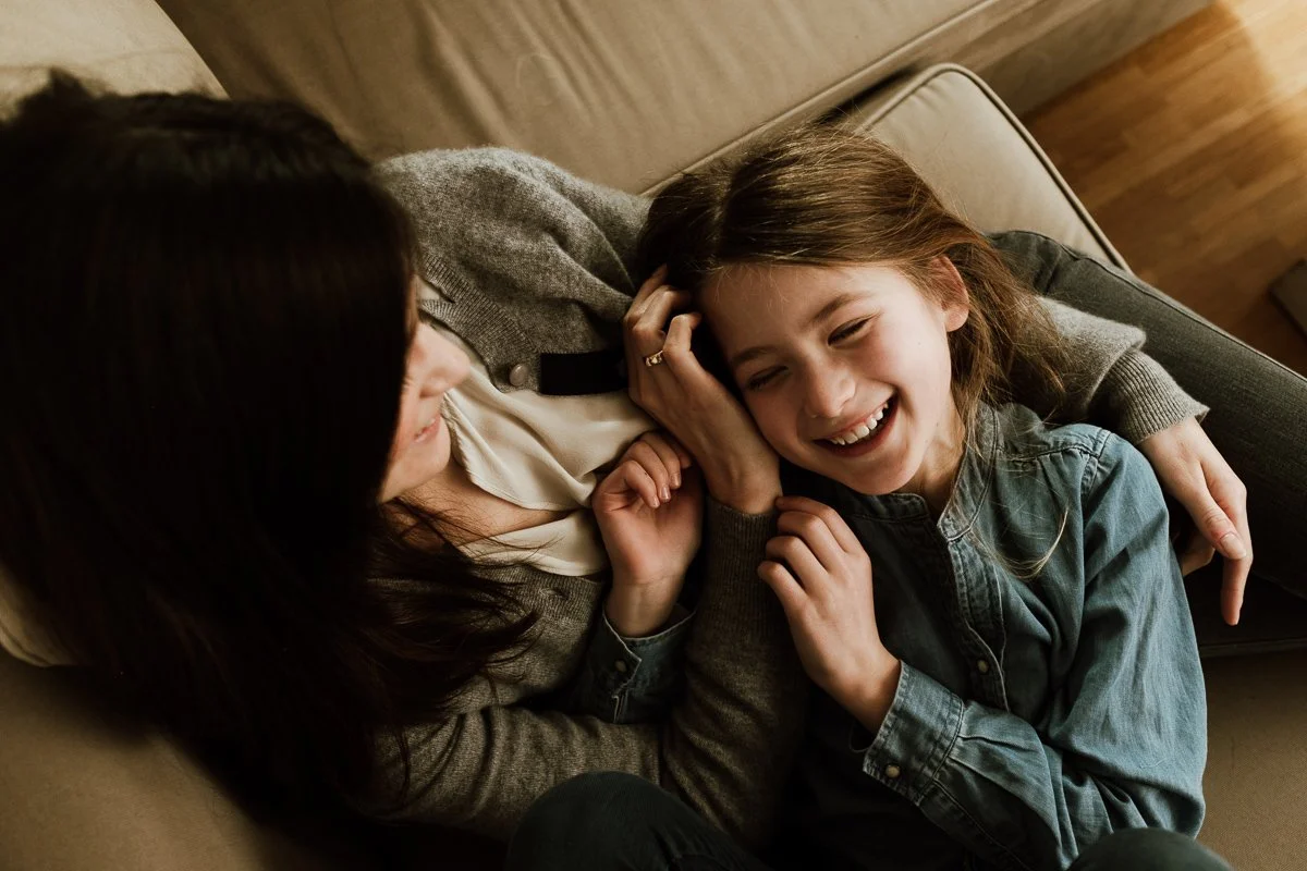 Werbefotografie: Mutter und Tochter lachen gemeinsam auf einem Sofa